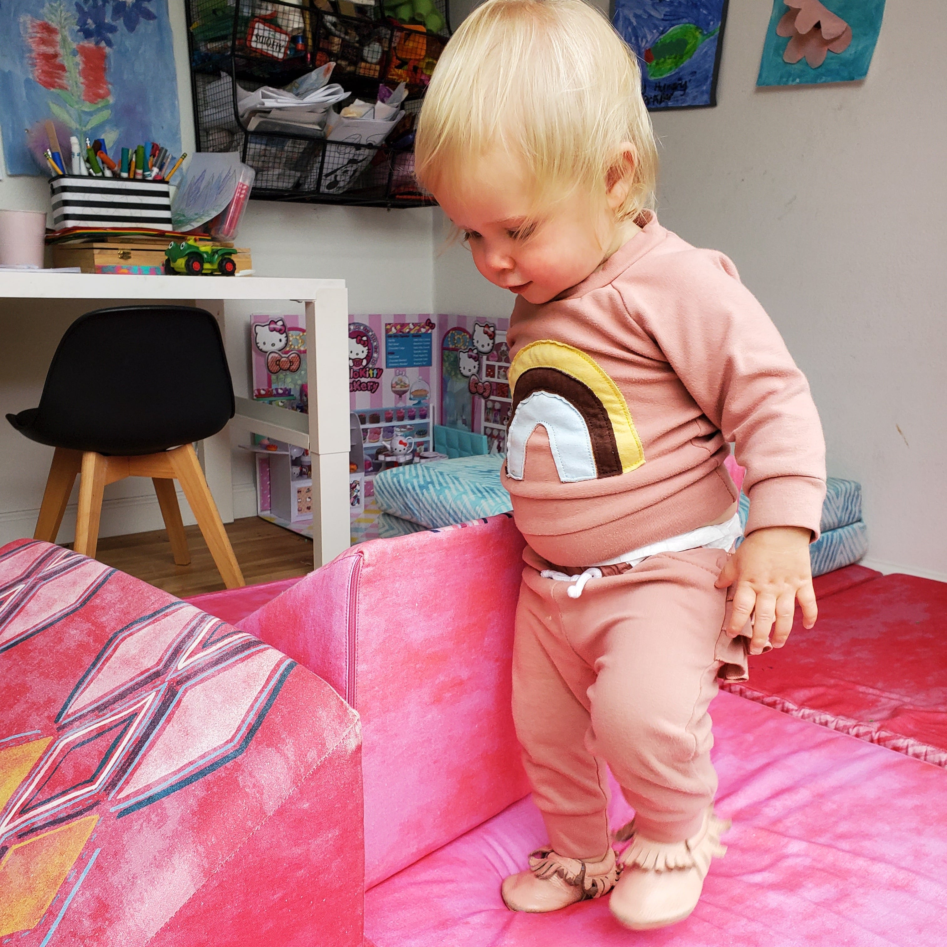 Child playing on a pink mat in a room with colorful decorations